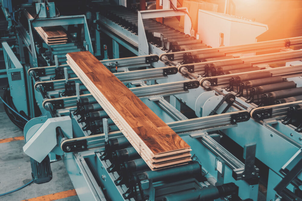 Automatisierte Holzbearbeitungsmaschine transportiert und verarbeitet Holzpaneele auf einer industriellen Förderanlage.