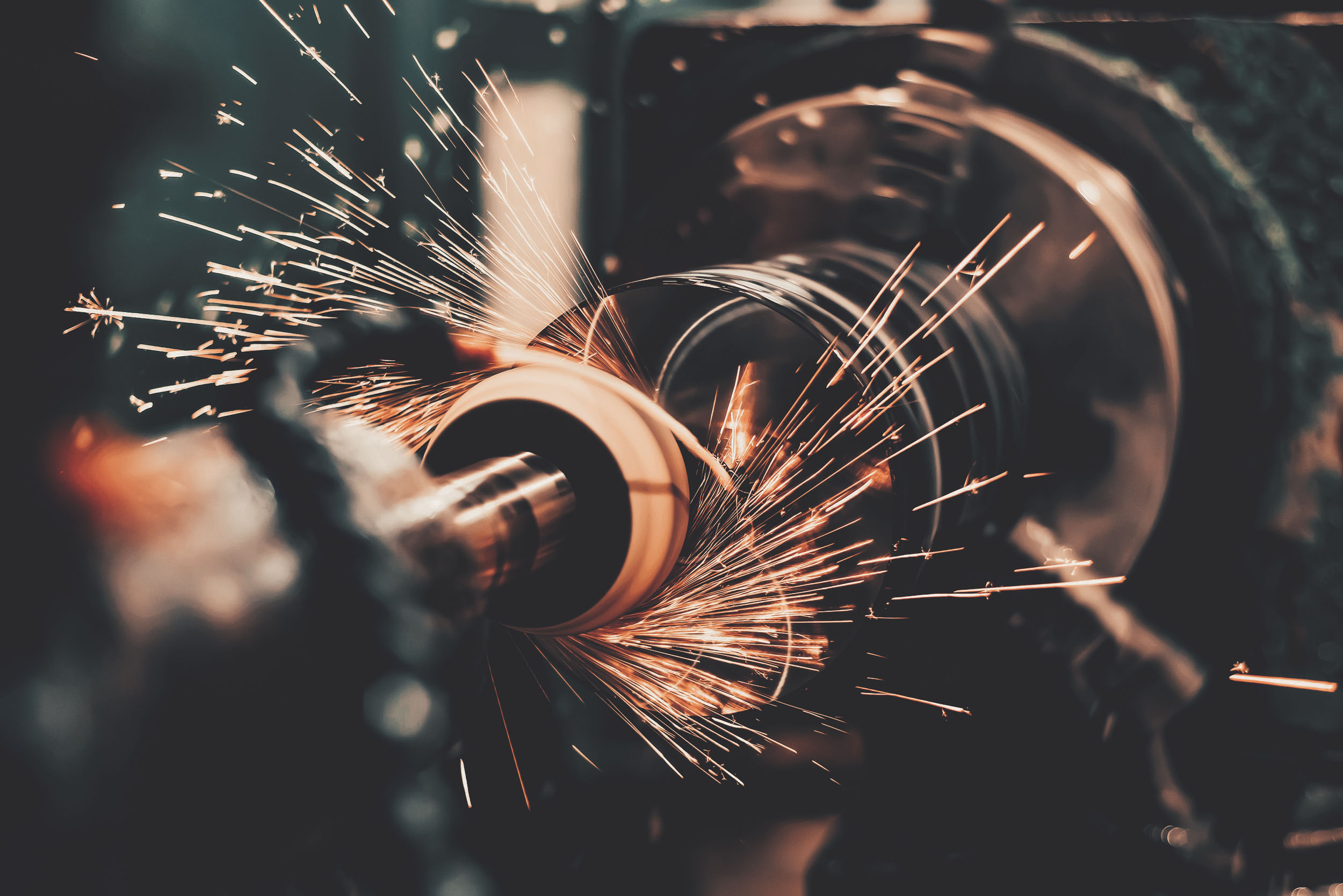 Nahaufnahme einer spanenden Werkzeugmaschine, die Funken beim Bearbeiten eines Metallteils erzeugt