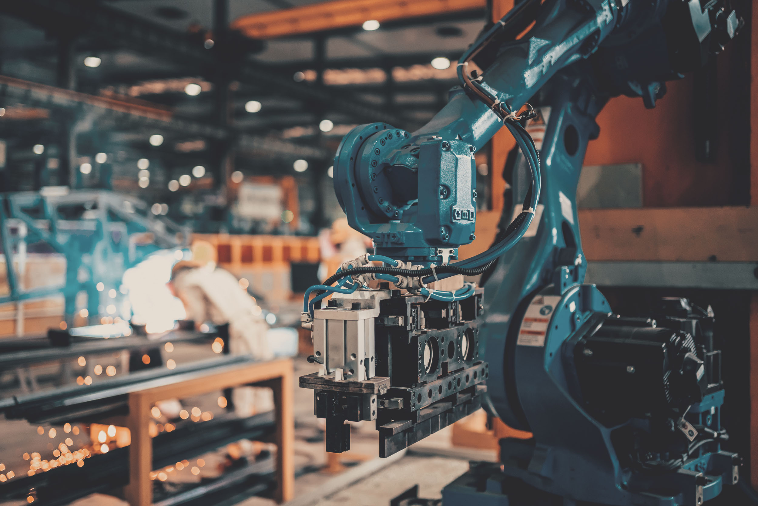 Industrieroboterarm mit Greifwerkzeug in einer Produktionshalle